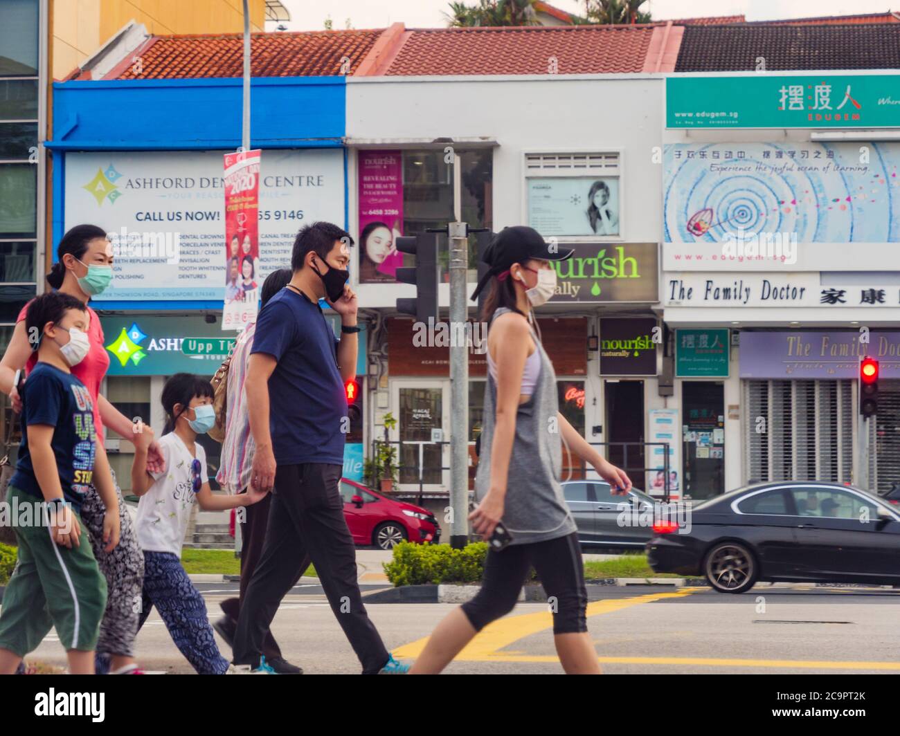 SINGAPORE – JUL 31, 2020 – A family with young children wearing protective face masks at a pedestrian crossing at Upper Thompson Road, Singapore. The Stock Photo