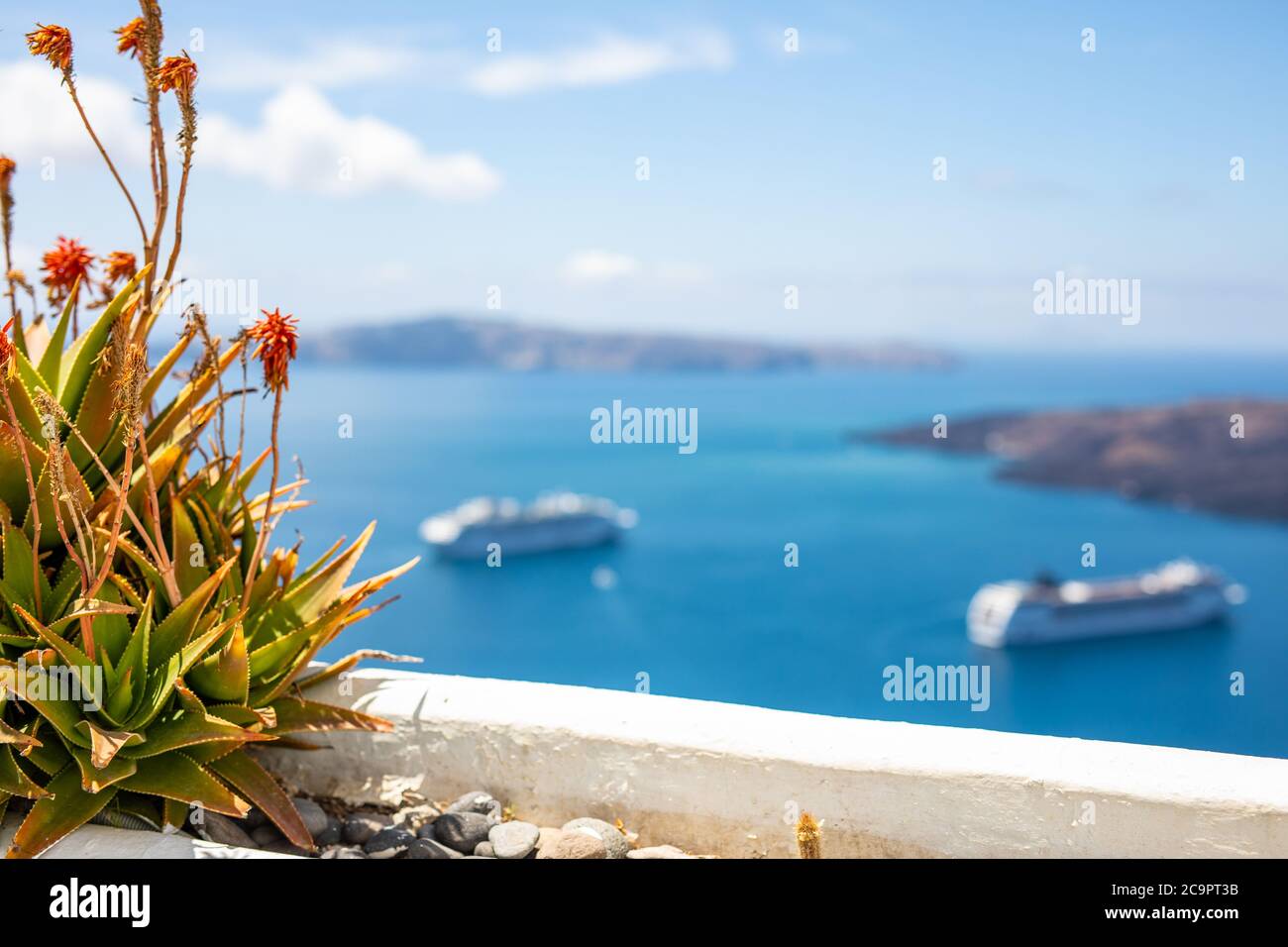 Peaceful view in Santorini, Greece with white architecture and pink flowers, cruise ships, Mediterranean summer mood, vacation and travel background. Stock Photo