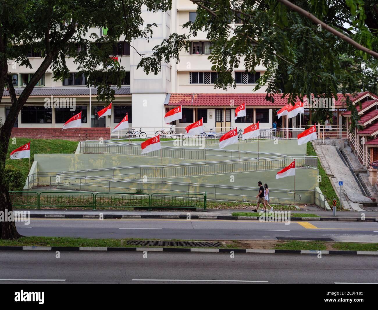 SINGAPORE – JUL 31, 2020 – People walk past a row of Singapore national flags placed at Sin Ming HDB residential estate in preparation for National Da Stock Photo