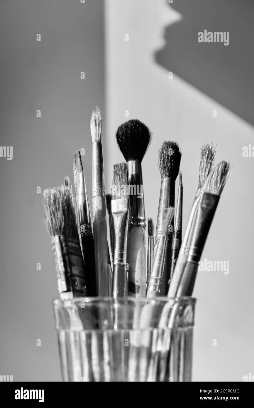 paint brushes set in glass on white background closeup, monochrome