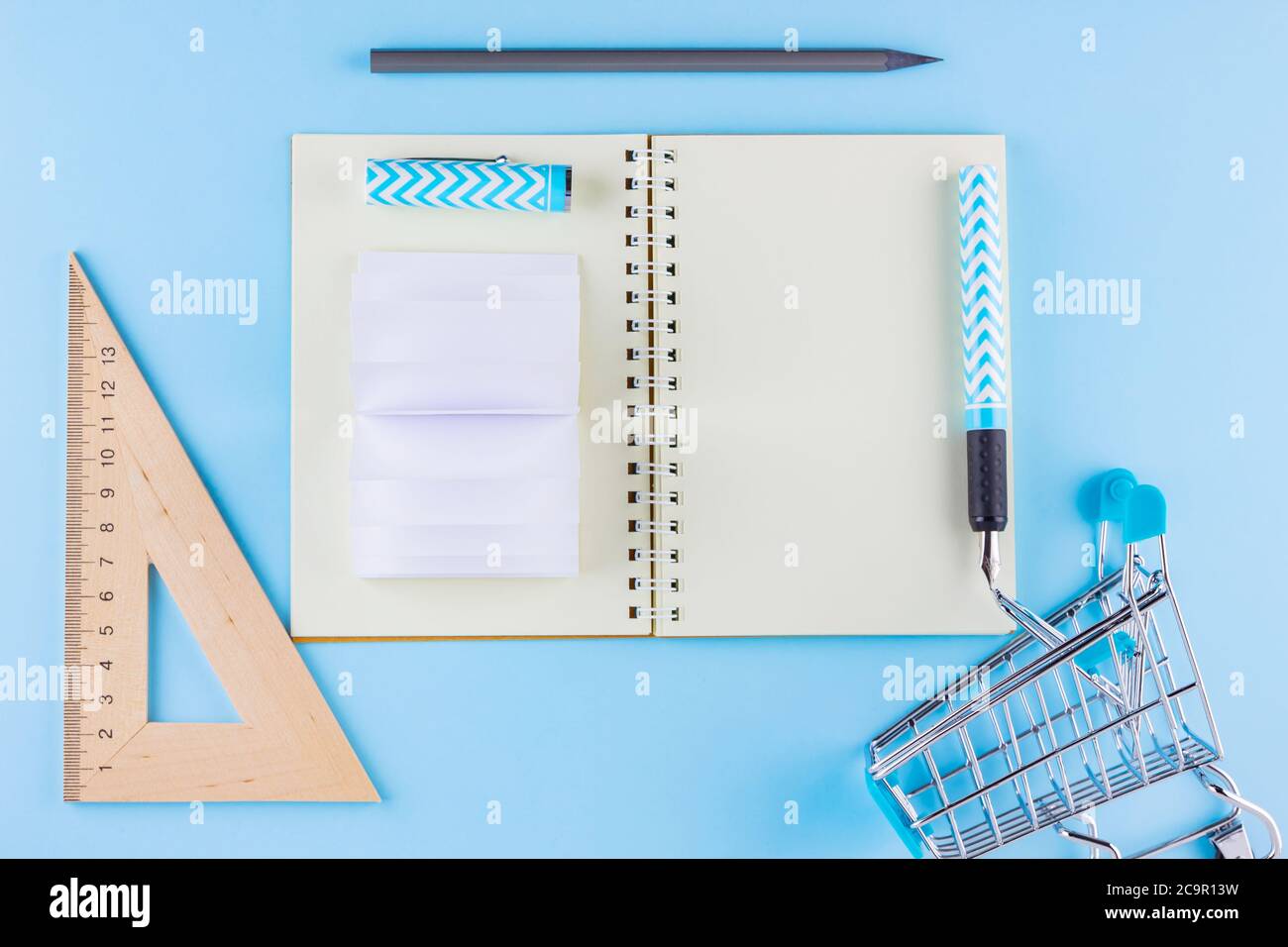 Back to school concept. Shopping cart and stationery on blue background