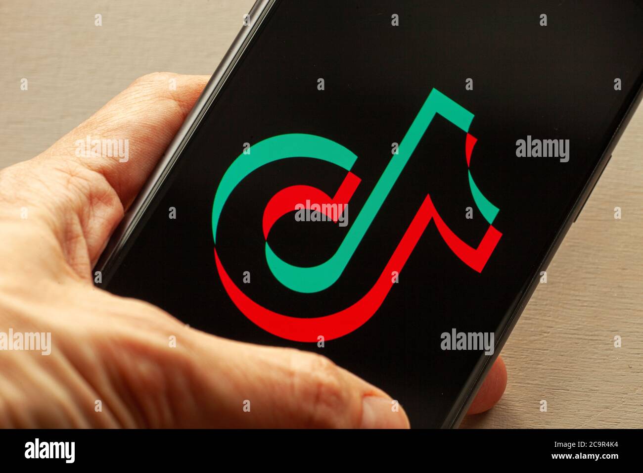 TikTok application icon on Apple iPhone 11 screen closeup. Hand
