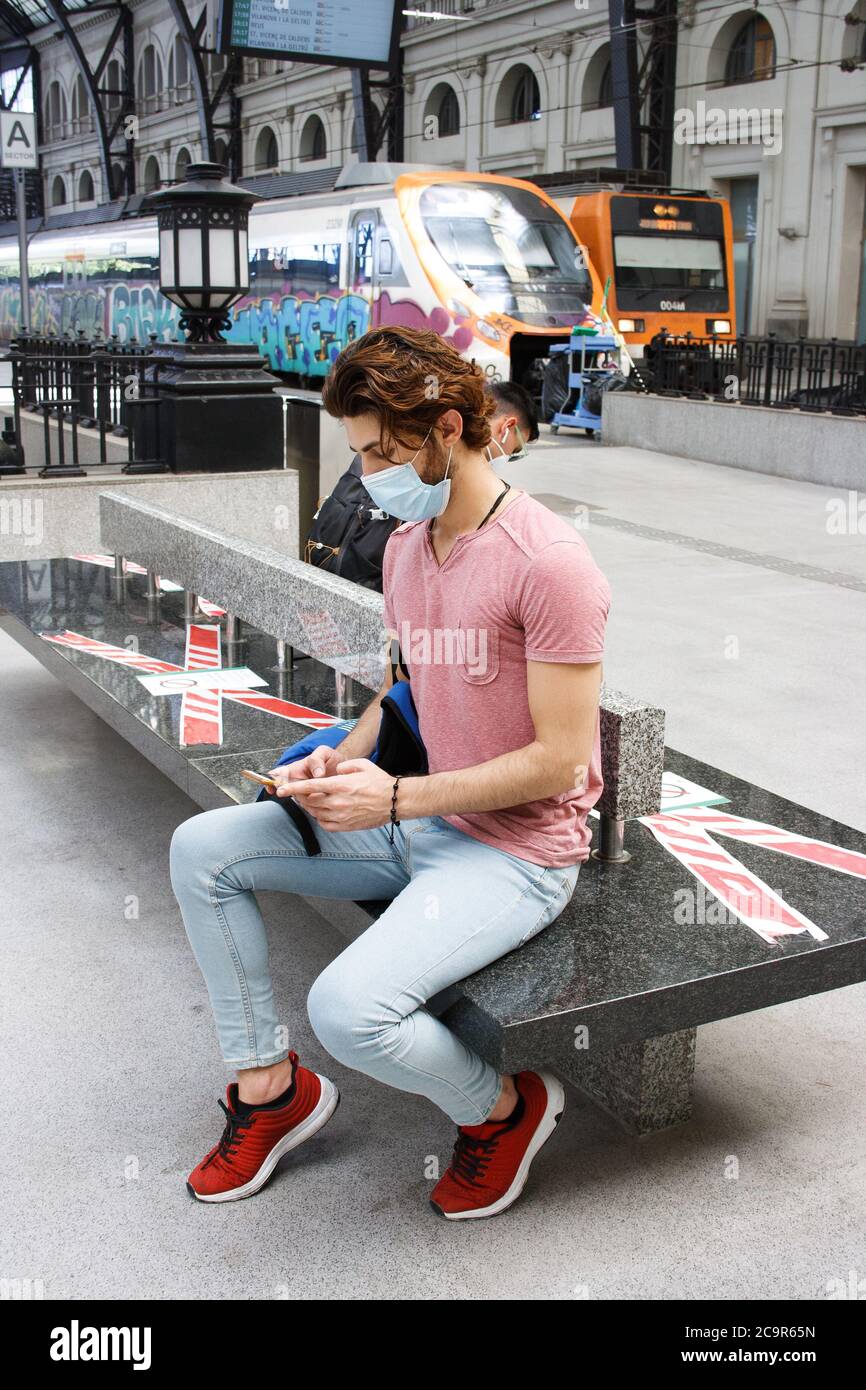 Young man waiting on train station. Keeping social distancing measures. Travel safe. Stock Photo