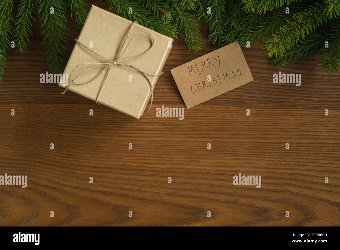 Flat lay christmas background with spruce twigs and brown gift box on ash wood surface Stock Photo