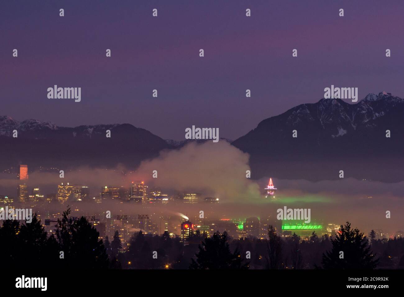 Vancouver's skyline at night - Aerial view from the Queens Elizabeth park in winter with snowed mountains in the background Stock Photo