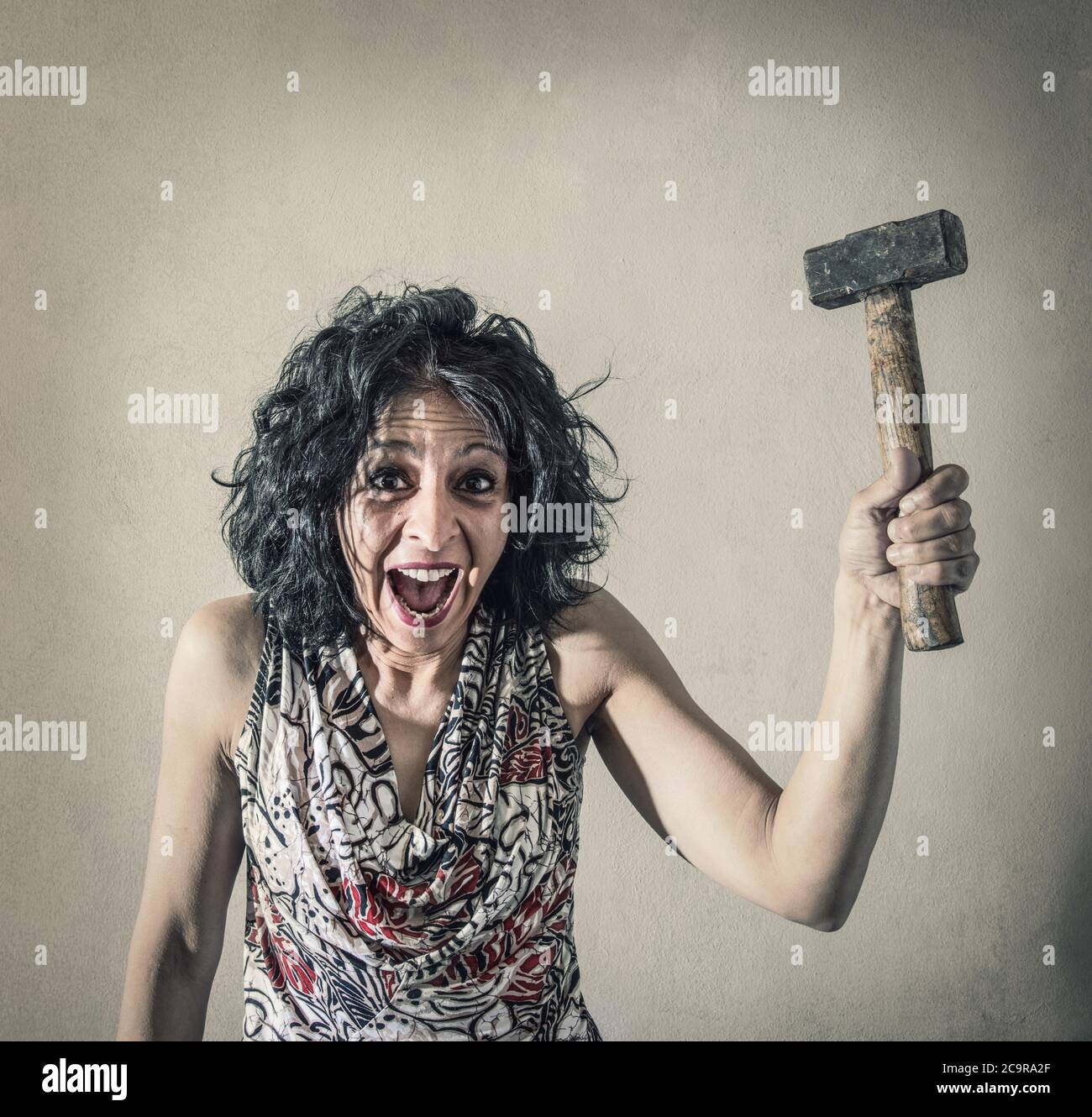 a Woman screaming with in hand a hammer Stock Photo