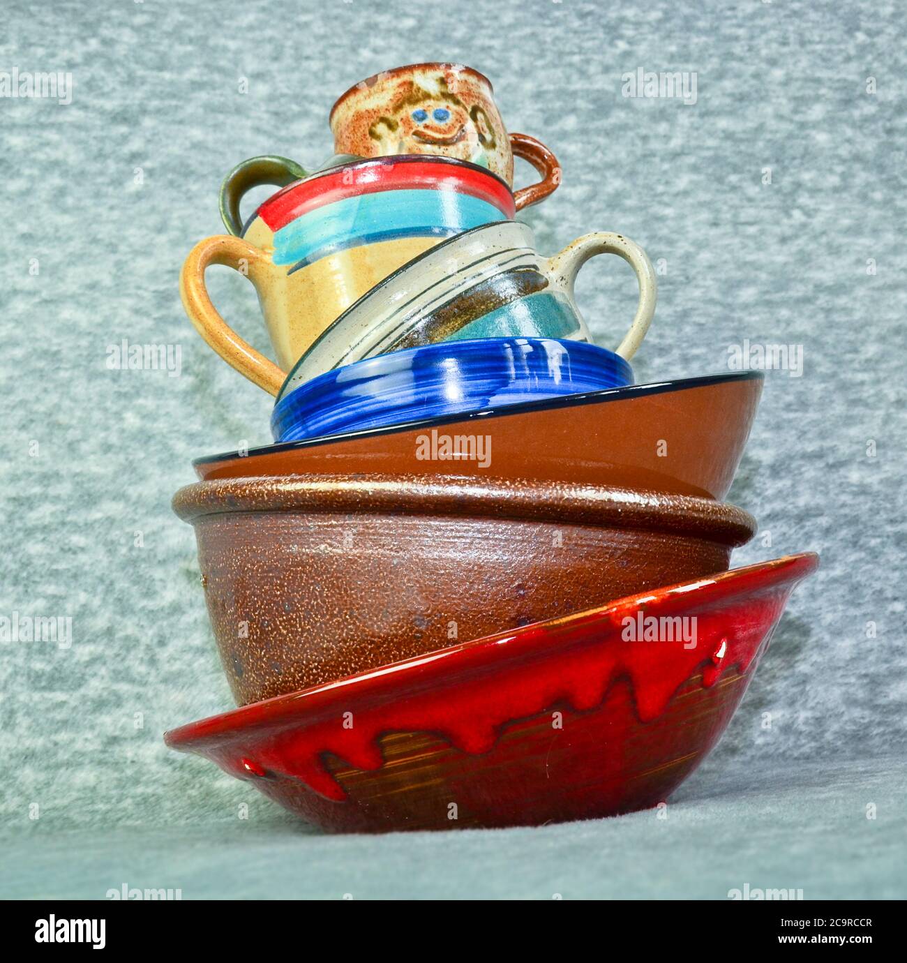 A small tower of high piled colourful crockery, bowls and cups Stock Photo