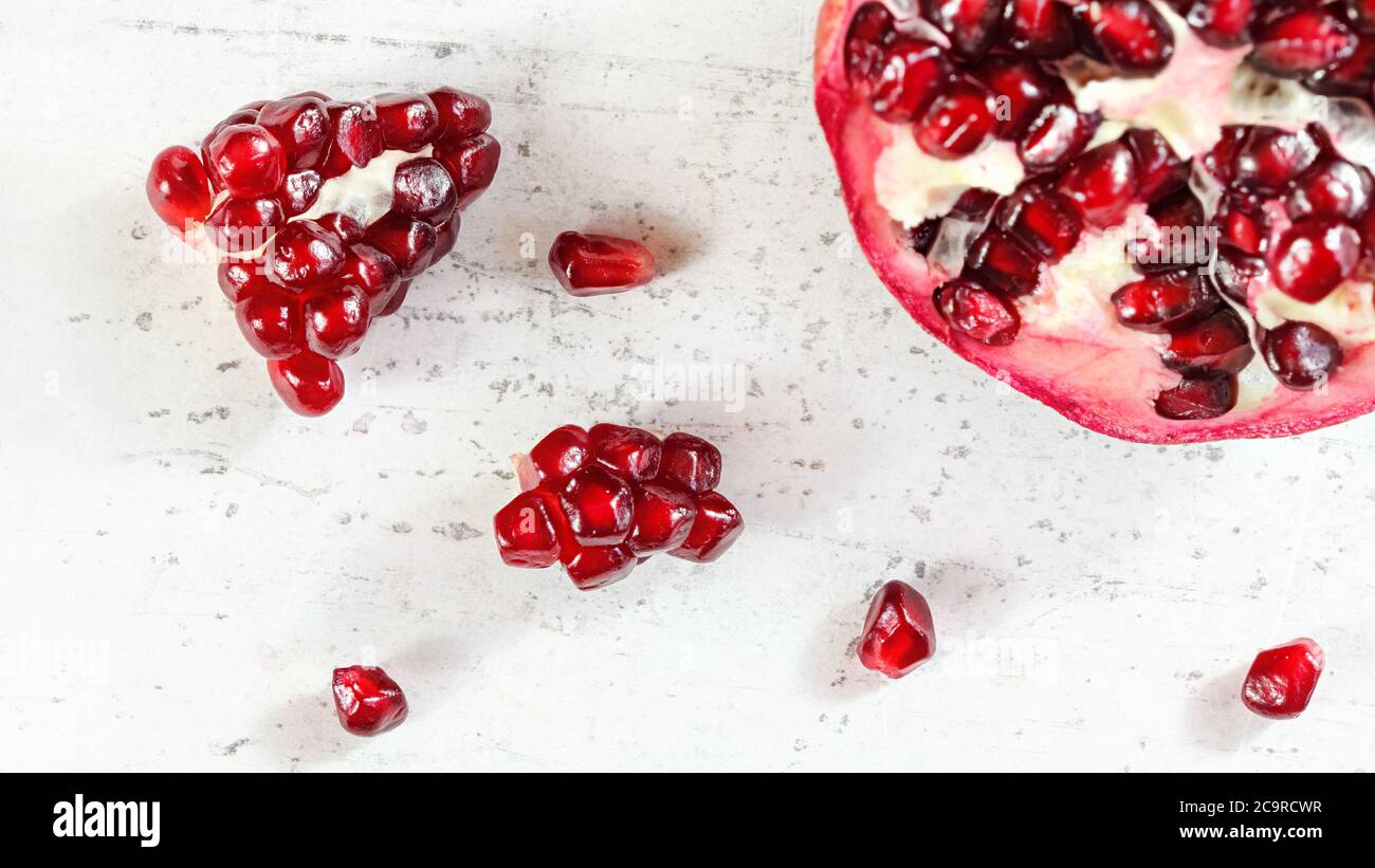 Tabletop view, pomegranate, gem like fruits scattered on white concrete board Stock Photo