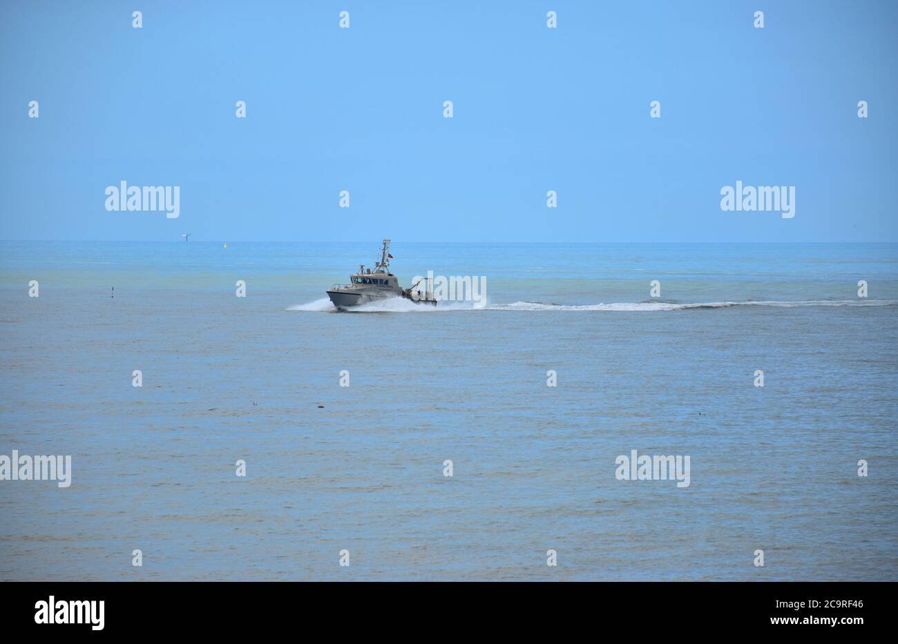 FPV Watchful from the Sussex IFCA patroling the coast off Hastings, Sussex, England, UK, with the Royal Sovereign lighthouse visable on the horizon. Stock Photo