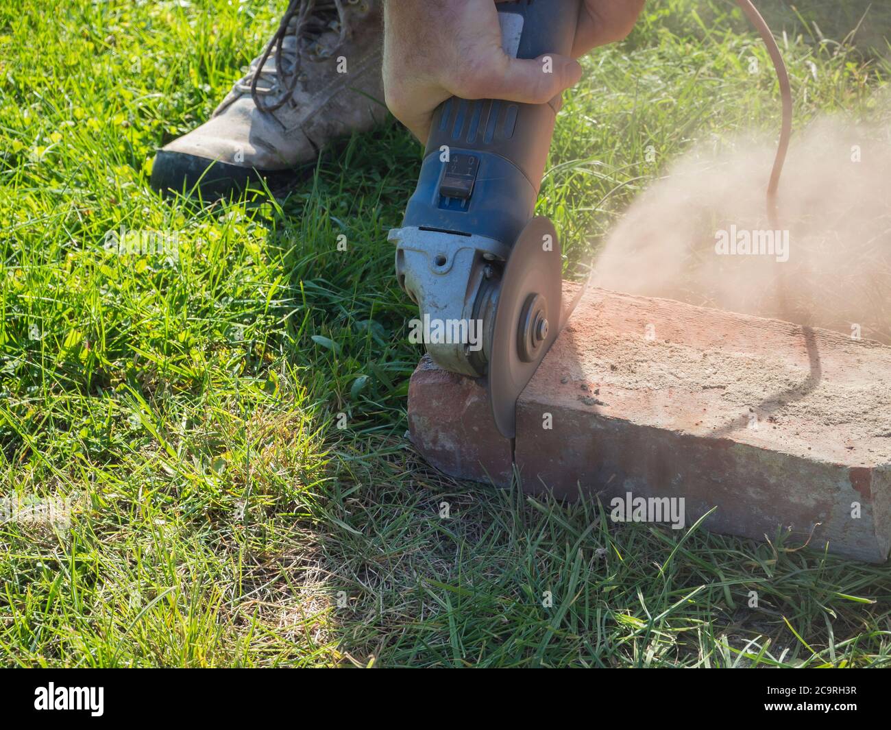 hands of man cutting brick working with portable circular saw on the
