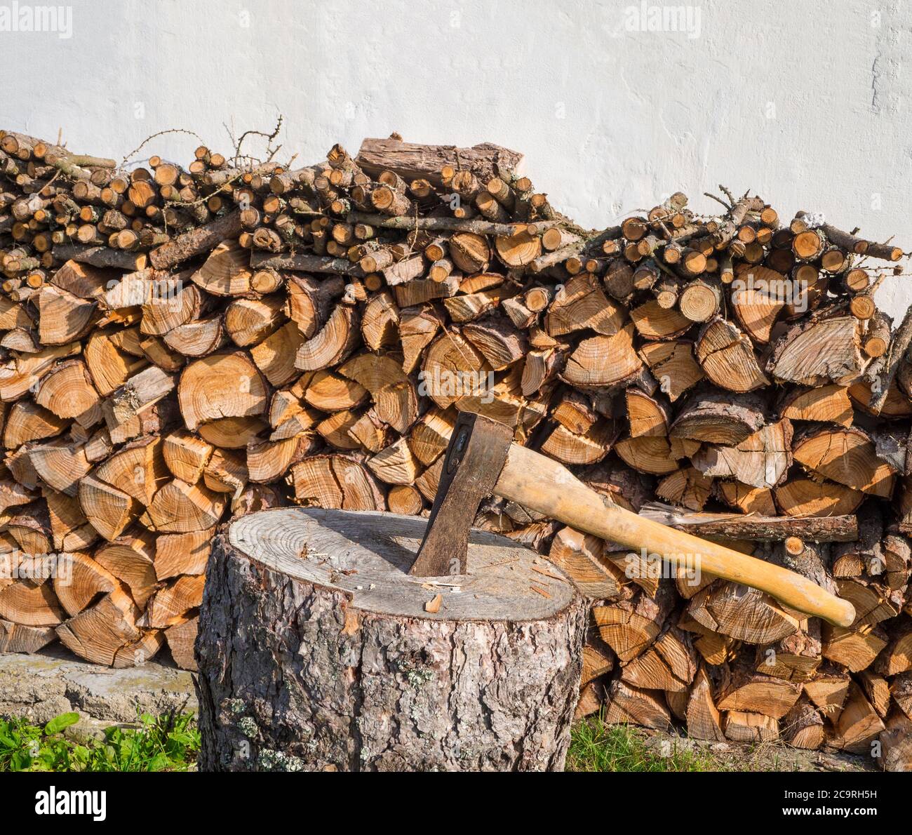 axe on the chopping block with chopped wood pile leveled on white wall