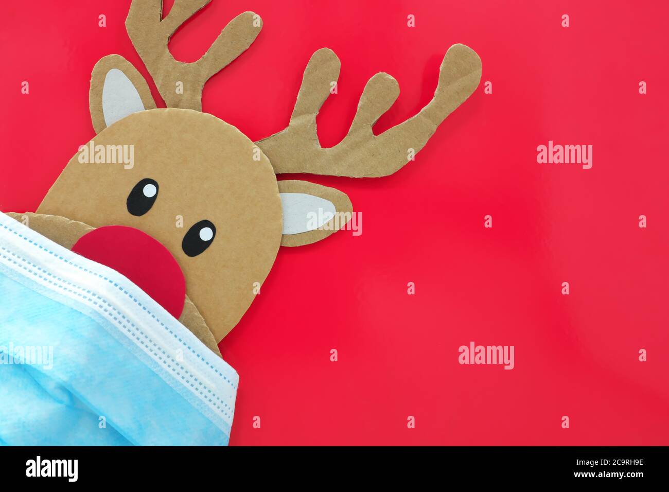 Cardboard cutout of cute reindeer peeking while wearing a face mask