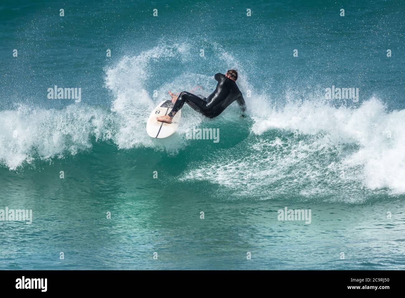 Spectacular action as a surfer wipes out as he rides a wave at Fistral in Newquay in Cornwall. Stock Photo