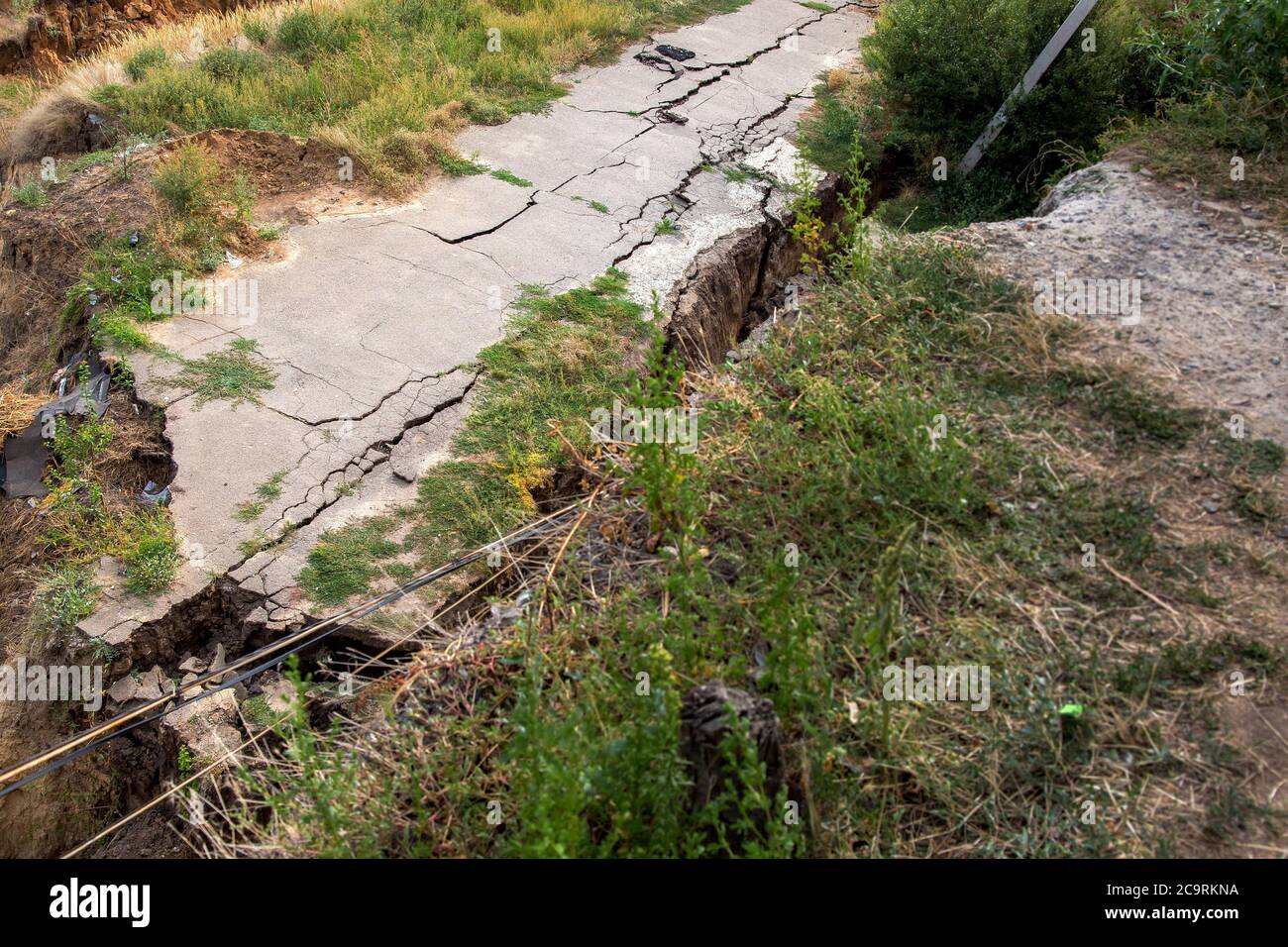 Consequences of a natural cataclysm of a landslide of soil, crack asphalt paving. Stock Photo