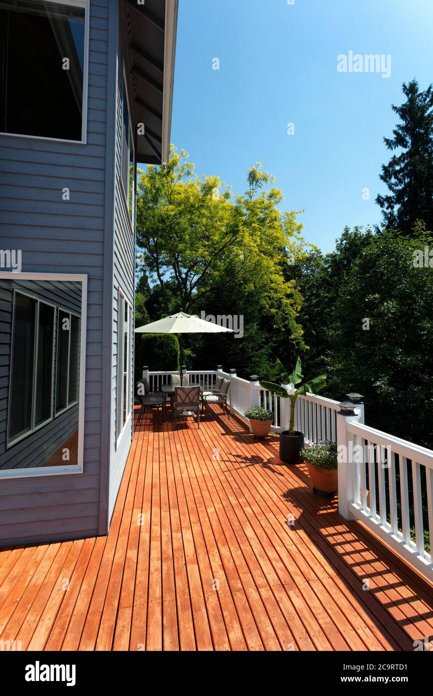 Outdoor home wooden cedar deck patio during lovely summer day with seasonal garden in vertical layout Stock Photo