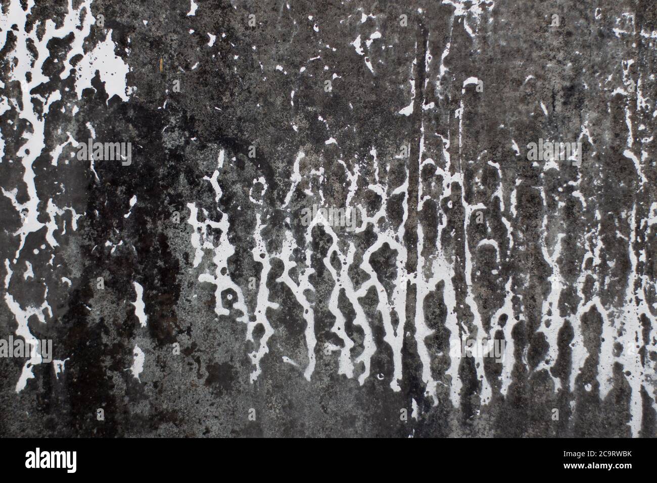 White paint dripping down on a dirty structured glass texture for