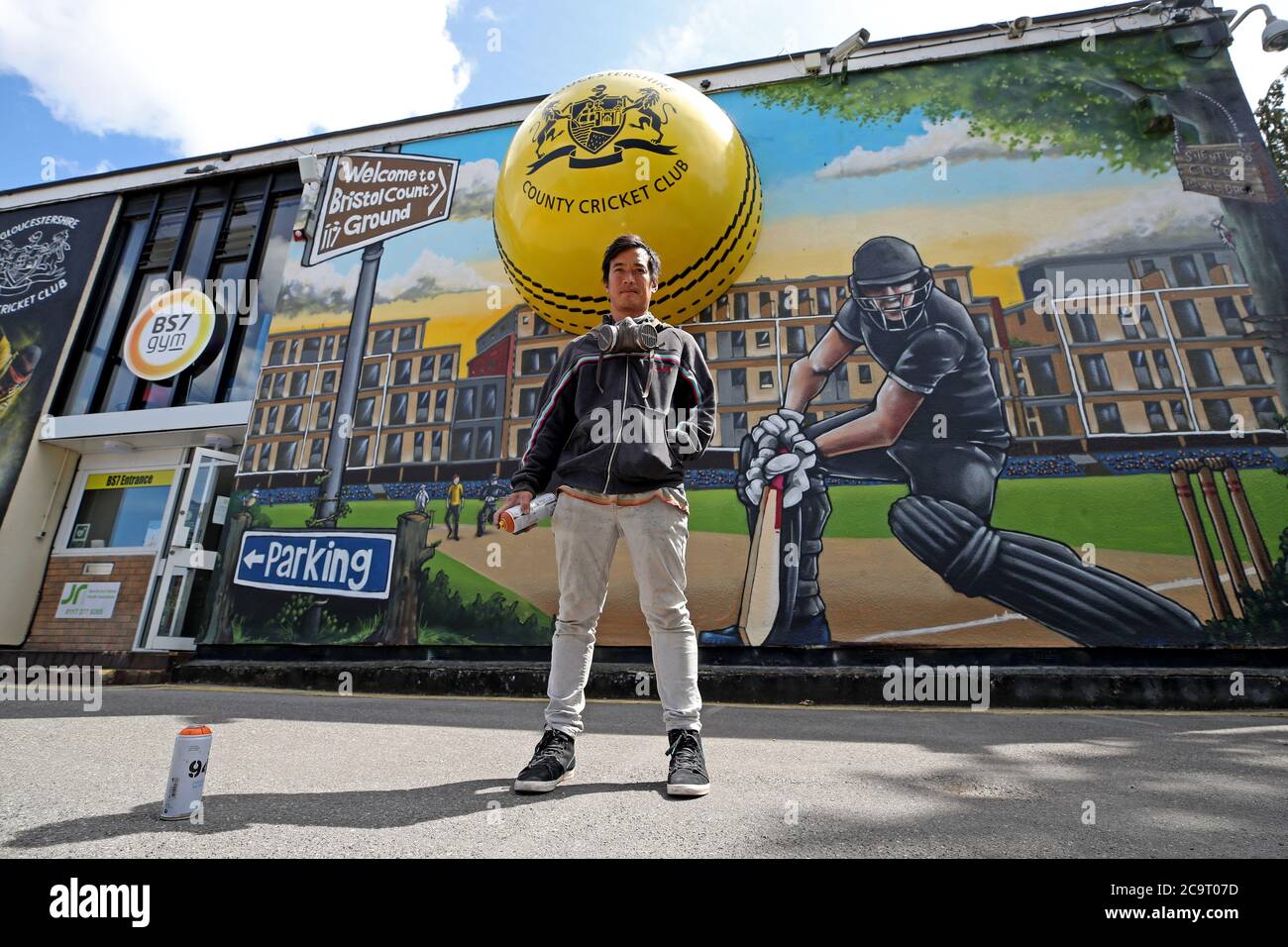 Graffiti artist Silent Hobo poses for a photo in front of his painted mural at Bristol County Ground. Stock Photo
