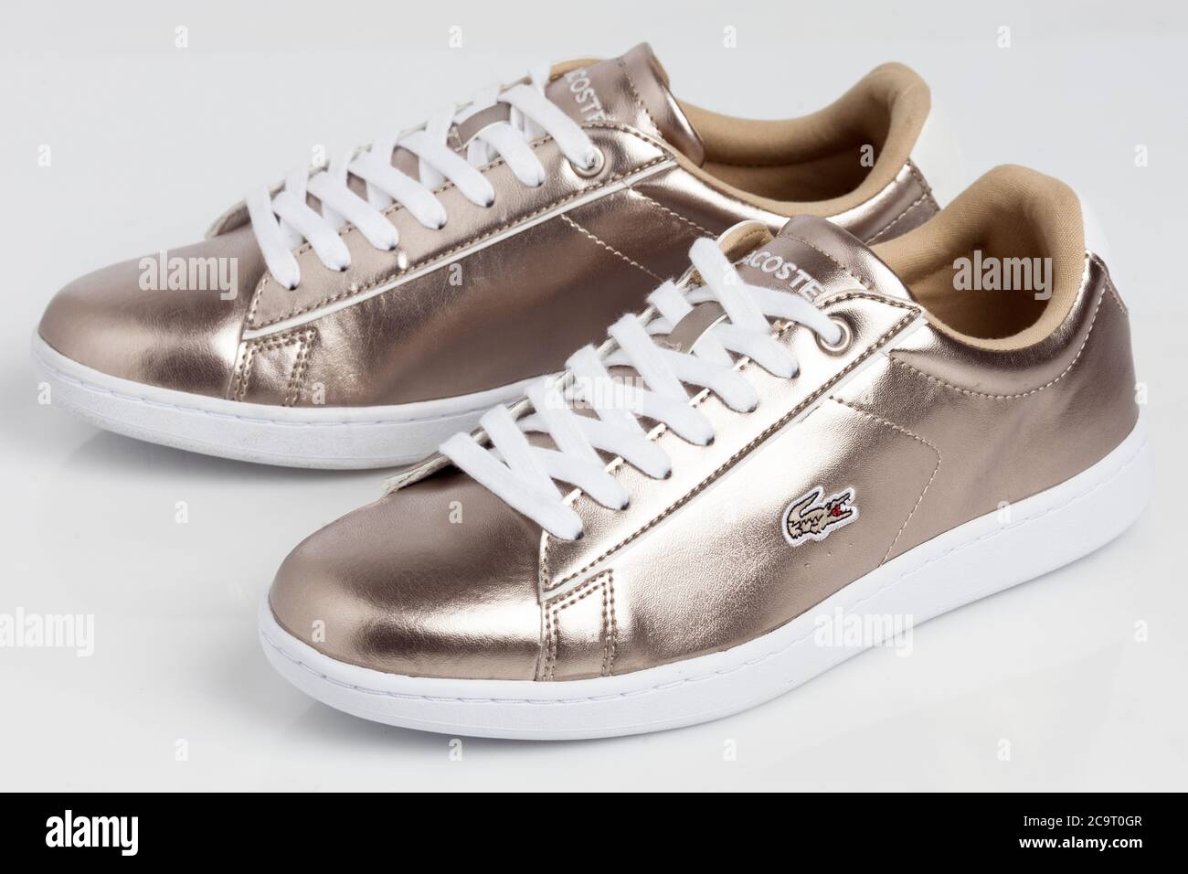 Gold shiny Lacoste sneakers on white background Stock Photo - Alamy