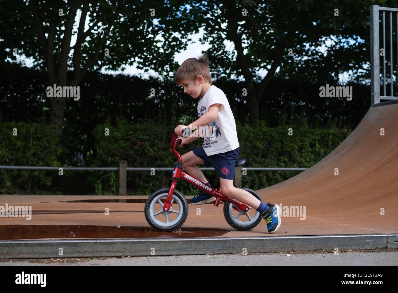 Four-year old boy playing on a Balance Bike at a skatepark in Ilkley West Yorkshire Stock Photo