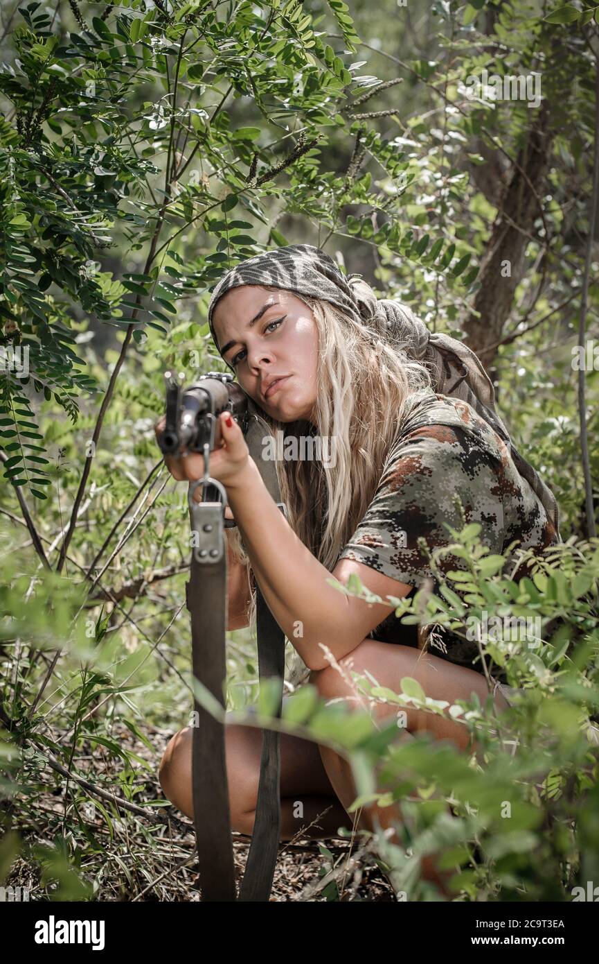 Beautiful and attractive woman soldier shooting with rifle machine gun in the forest. Female  army nature outdoor military combat training. Femme fata Stock Photo