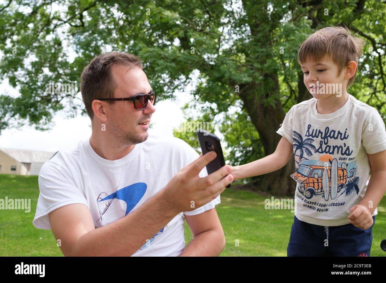 A father and son sharing a phone conversation outdoors Stock Photo