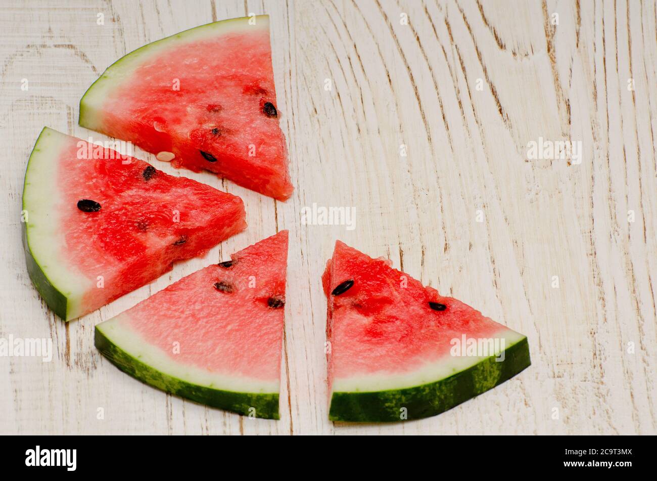 Triangular slices of watermelon on a light wooden background, with ...