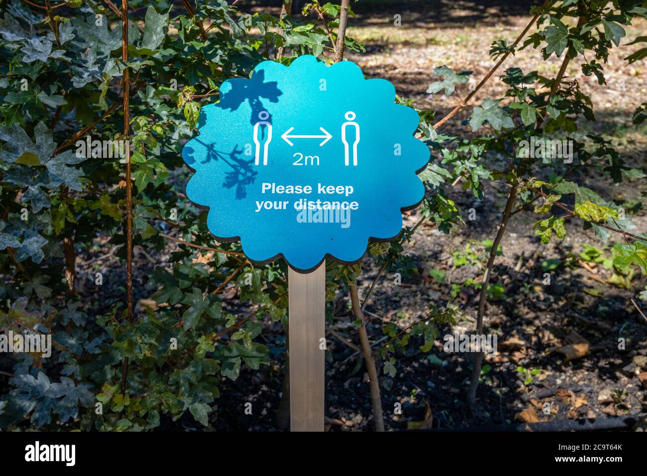 Blue 2m social distancing reminder sign for visitors to Wakehurst,  botanic gardens in West Sussex managed by the Royal Botanic Gardens, Kew Stock Photo