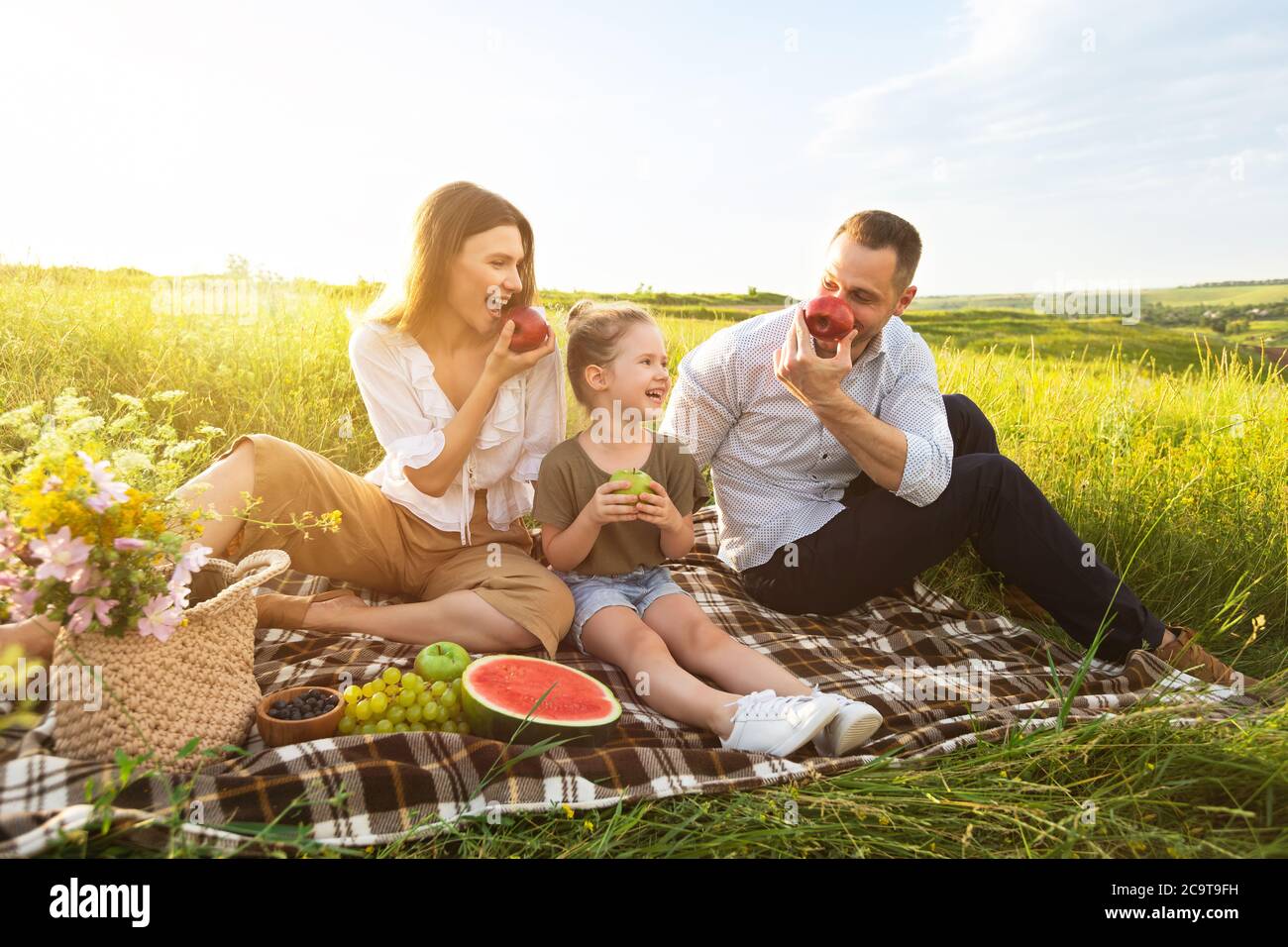 Young family playing with fruits on a picnic outdoor Stock Photo