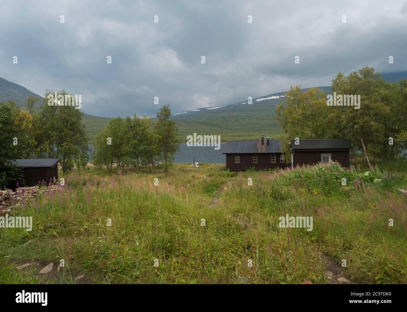STF Teusajaure Fjallstuga Mountain cabin hut with blue Teusajaure lake, green hills, birch forest and footpath of Kungsleden hiking trail. Lapland nat Stock Photo