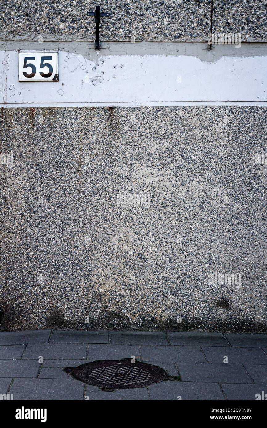 Aged weathered street wall with number 55. Architecture detail background. Stock Photo