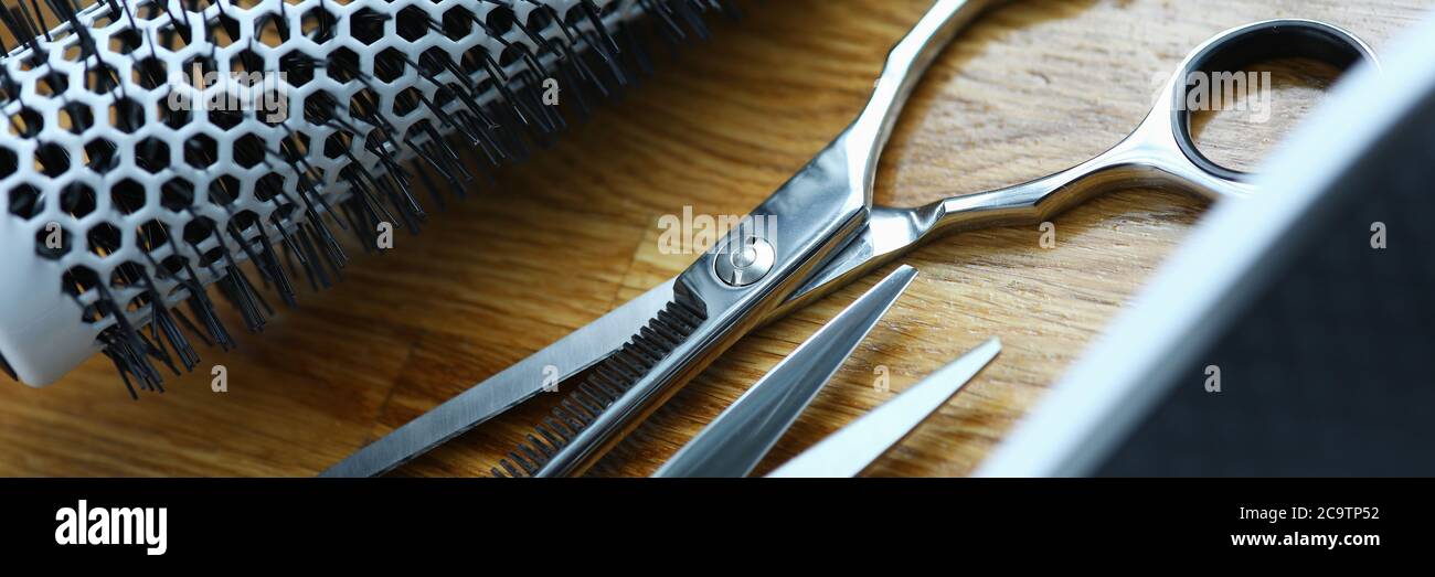Clipper and comb lie on wooden table in hairdresser closeup Stock Photo