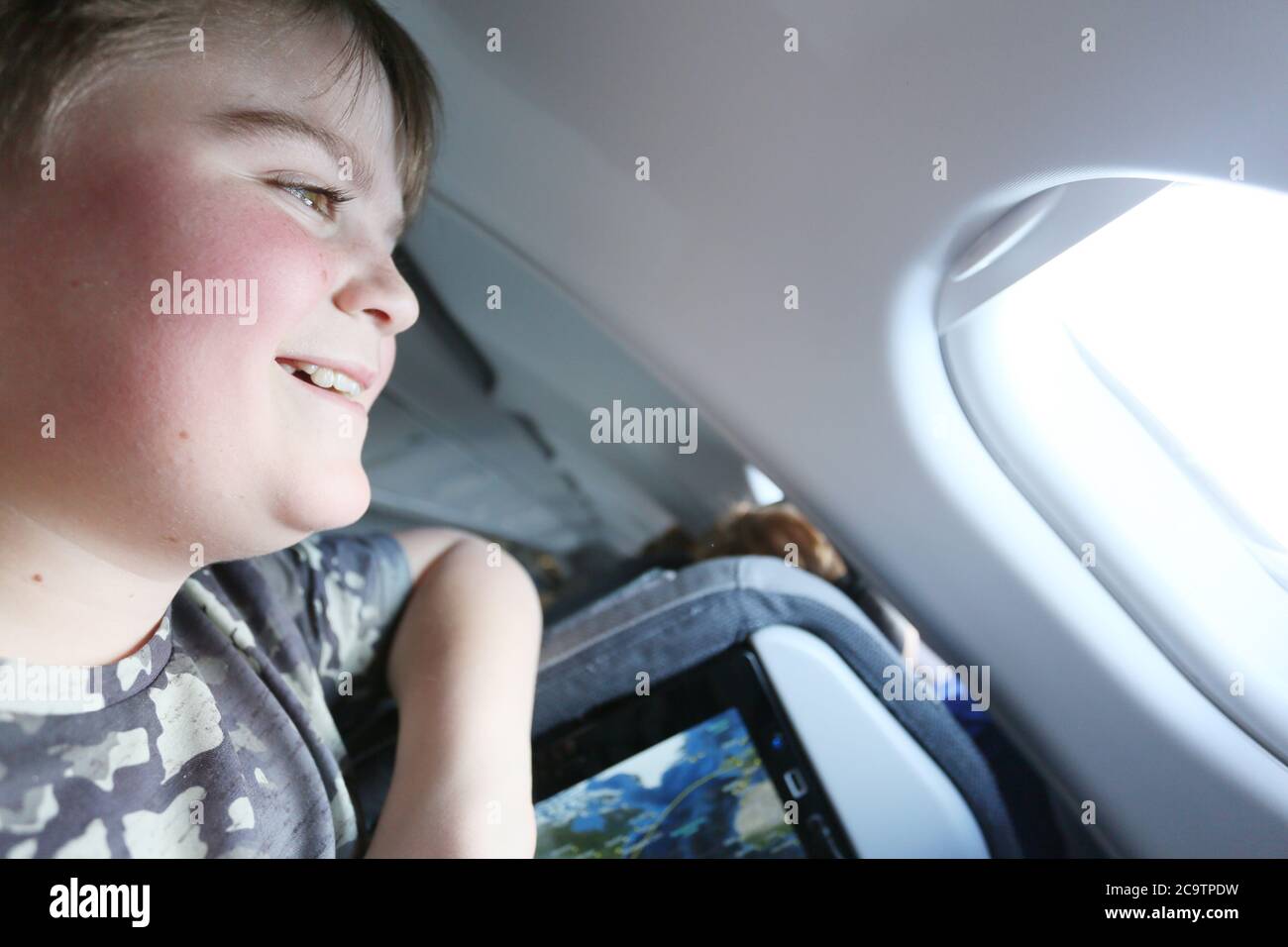boy on a plane to mexico looking out of the aircraft portal window Stock Photo