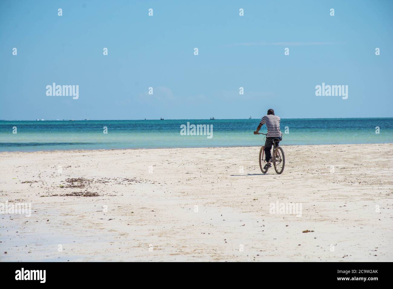 Man riding on a bike at the diani beach in Kenya. Beautiful view on ocean. Stock Photo
