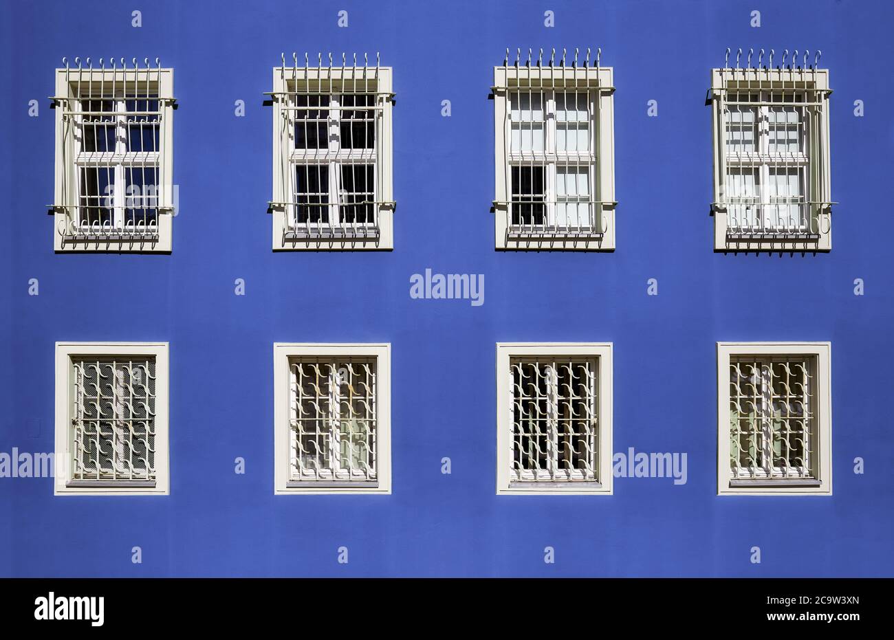 Barred windows in a blue wall. Stock Photo