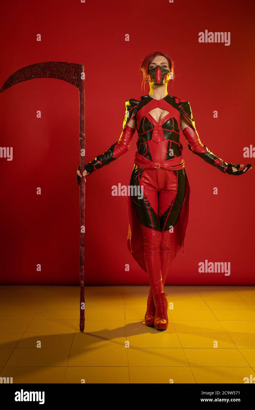 Actress woman in mask and costume of fictional fantasy character posing on red background Stock