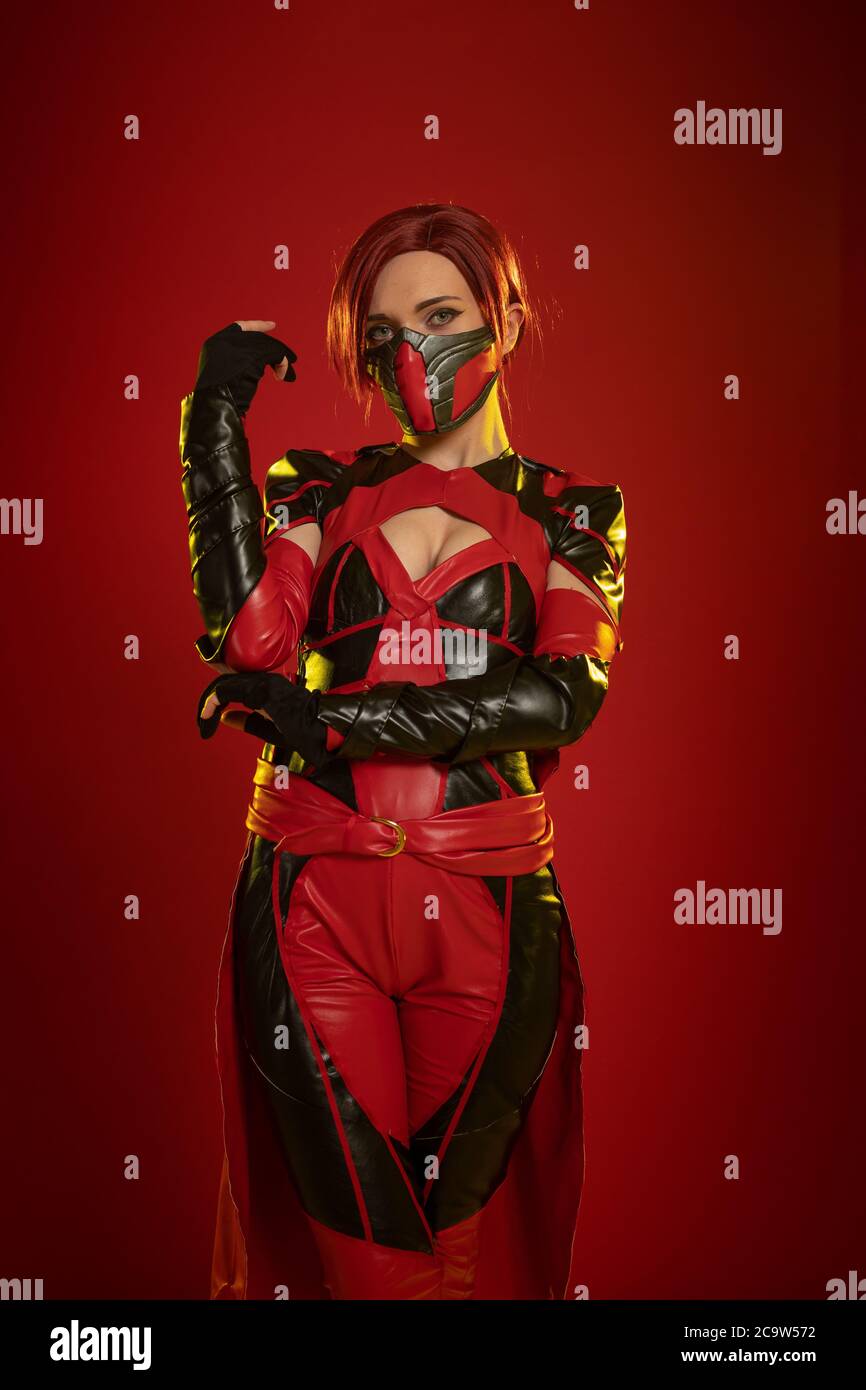 Actress woman in mask and costume of fictional fantasy character posing on red background Stock Photo