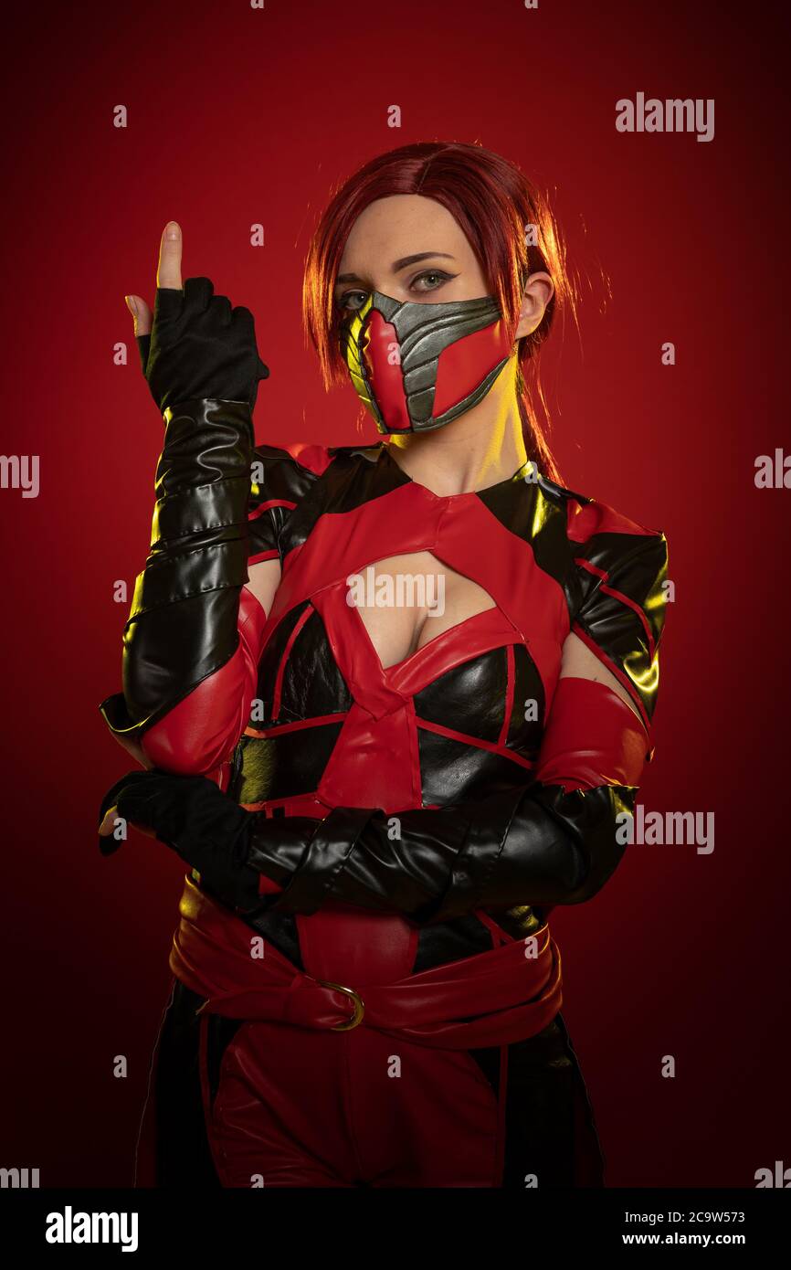 Actress woman in mask and costume of fictional fantasy character posing on red background Stock