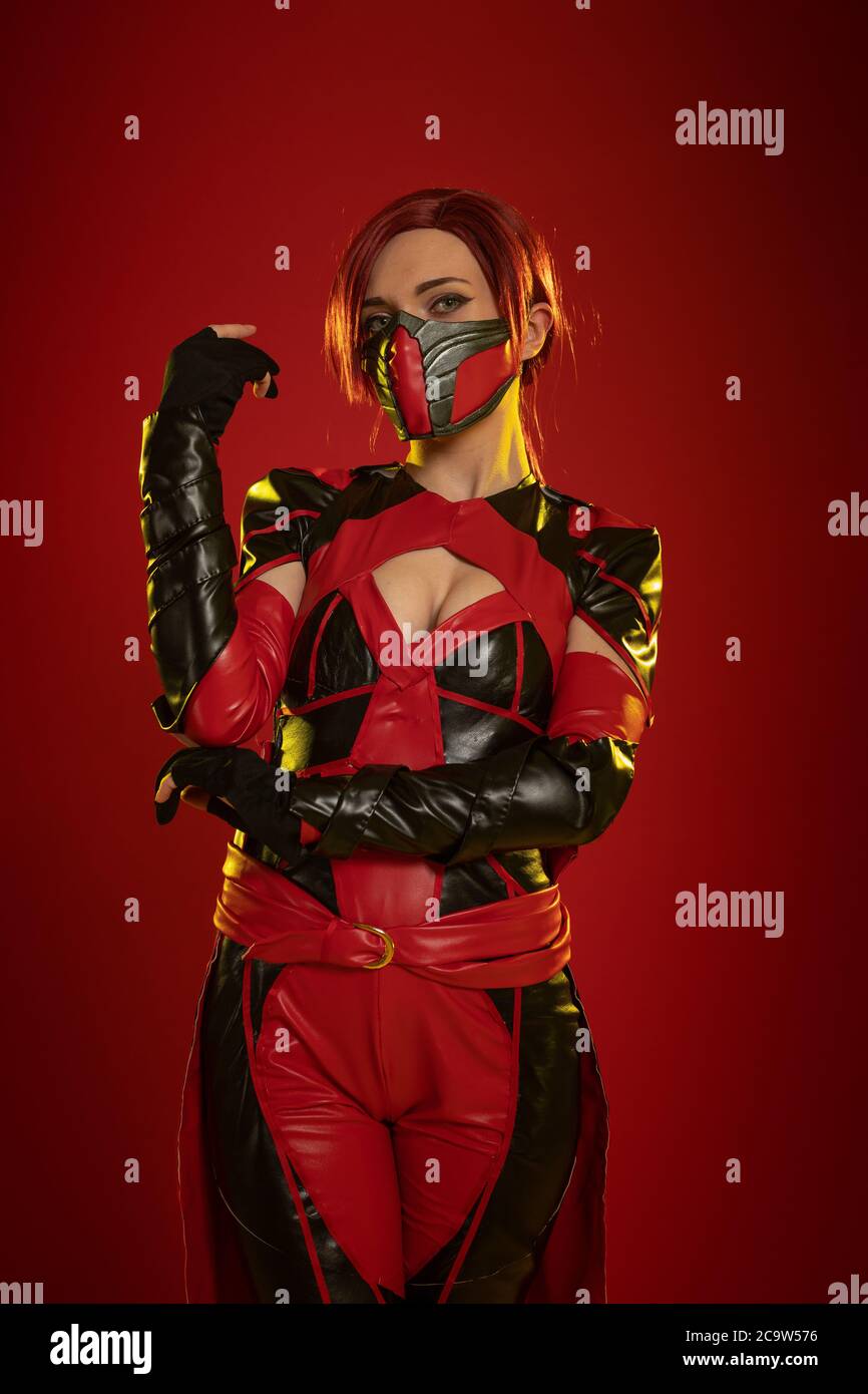 Actress woman in mask and costume of fictional fantasy character posing on red background Stock