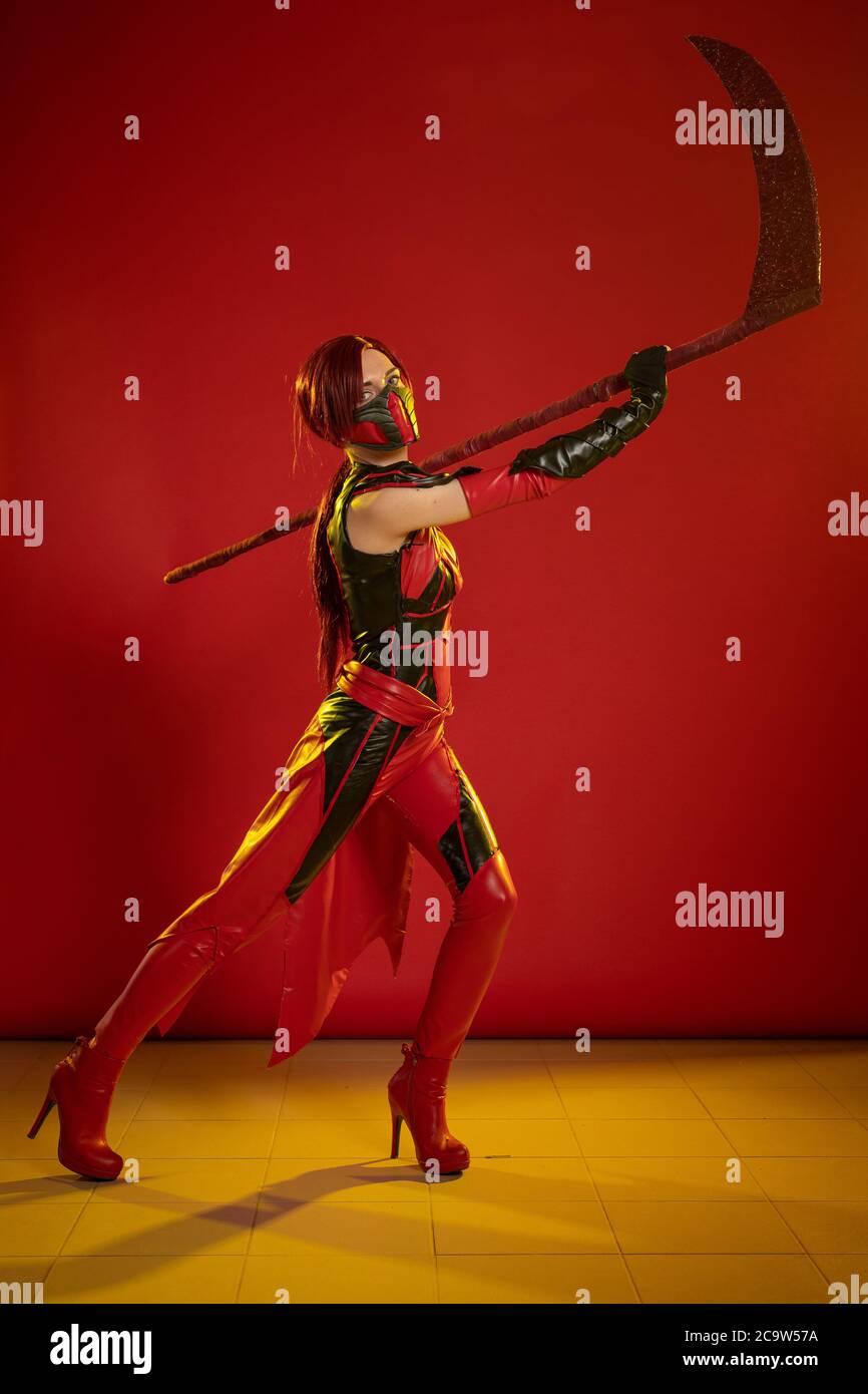 Actress woman in mask and costume of fictional fantasy character posing on red background Stock Photo