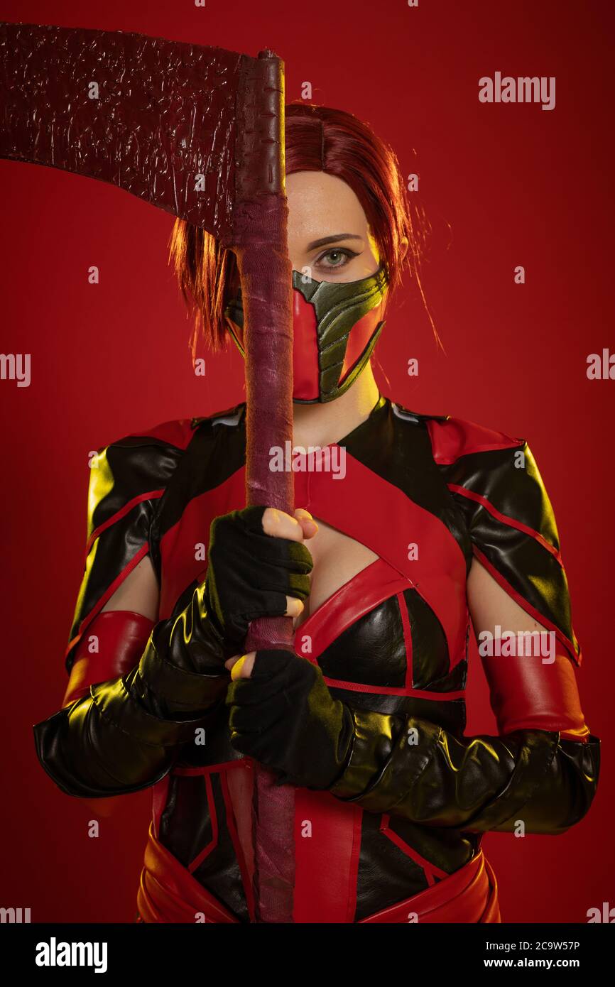 Actress woman in mask and costume of fictional fantasy character posing on red background Stock