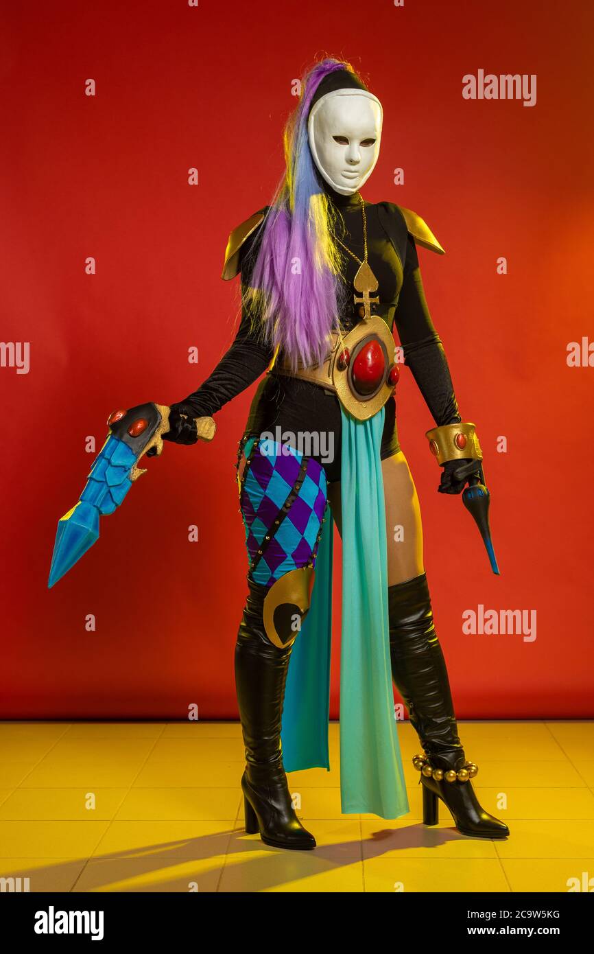 Actress woman in mask and costume of fictional fantasy character posing on red background Stock