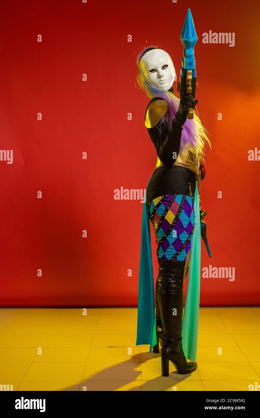 Actress woman in mask and costume of fictional fantasy character posing on red background Stock Photo