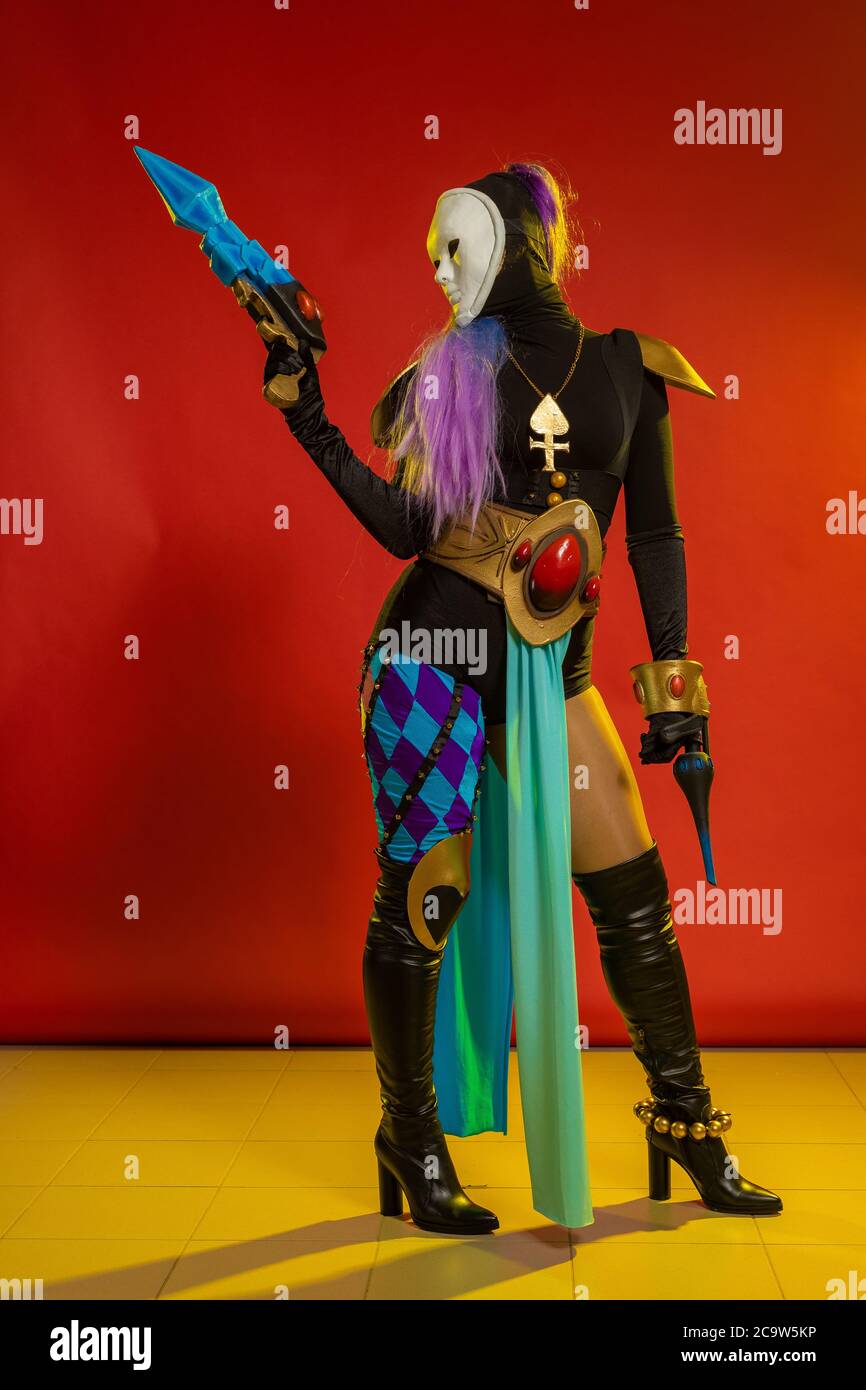 Actress woman in mask and costume of fictional fantasy character posing on red background Stock Photo