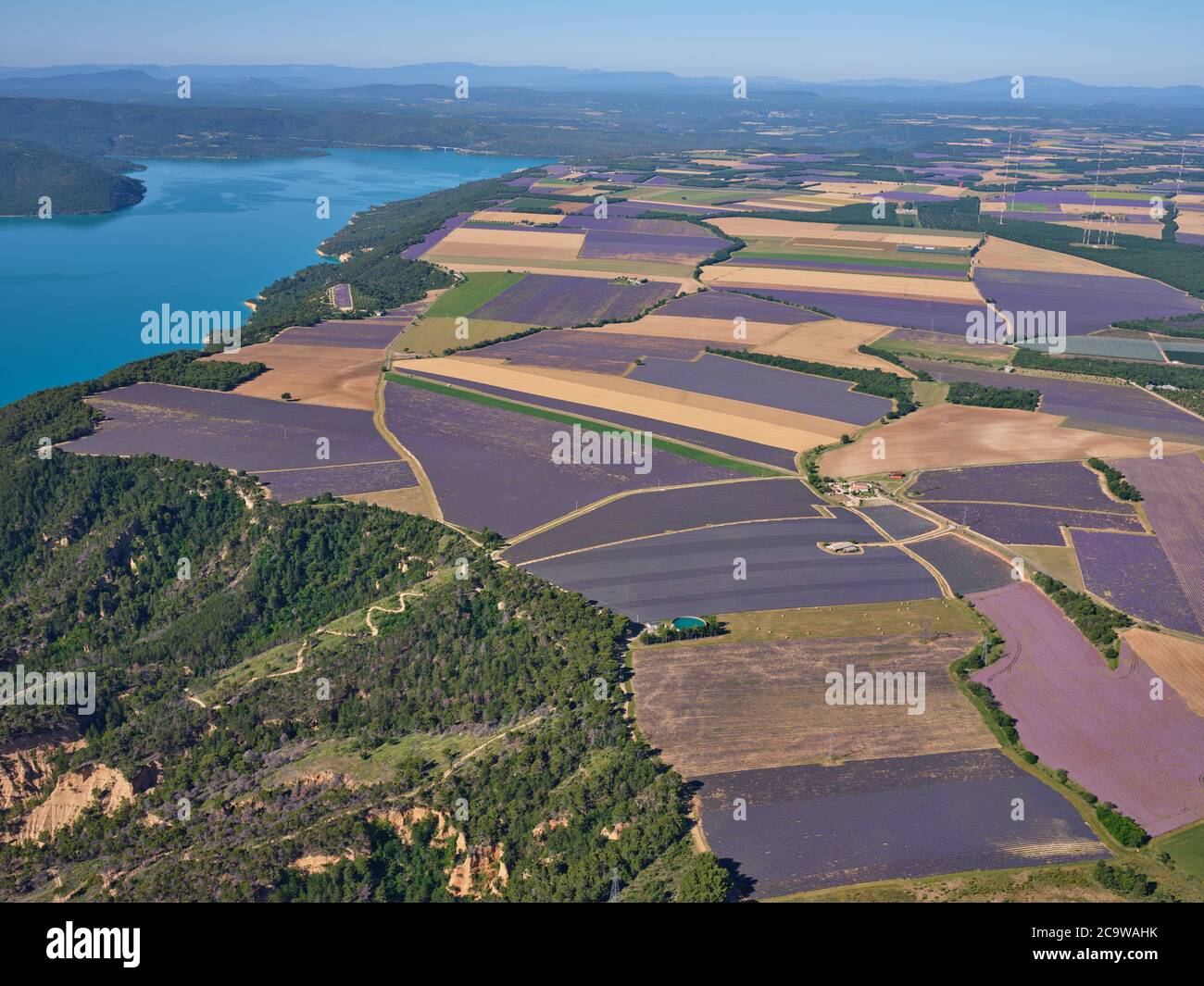 AERIAL VIEW. Lavender fields on the Valensole Plateau overlooking Lake Sainte-Croix. Moustiers-Sainte-Marie, Provence, France. Stock Photo