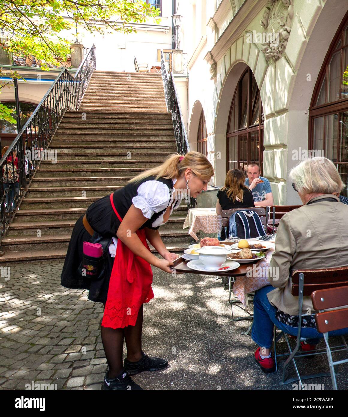 A waitress serves lunch to a customer, Outdoor Beer Garden, Hofbrauhaus, Munich, Bavaria, Germany. Stock Photo