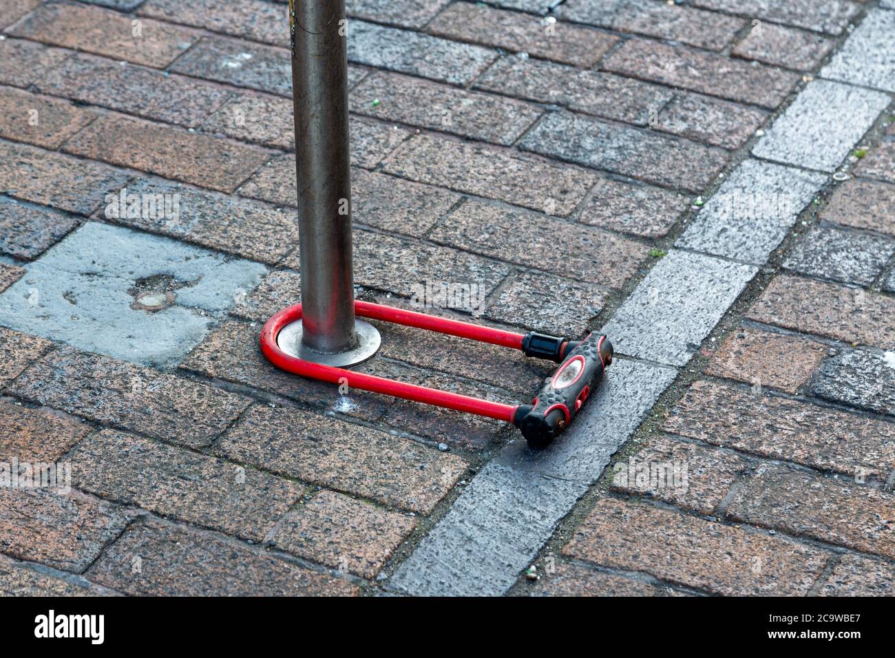 A D lock bike lock locked around a pole on the street Stock Photo
