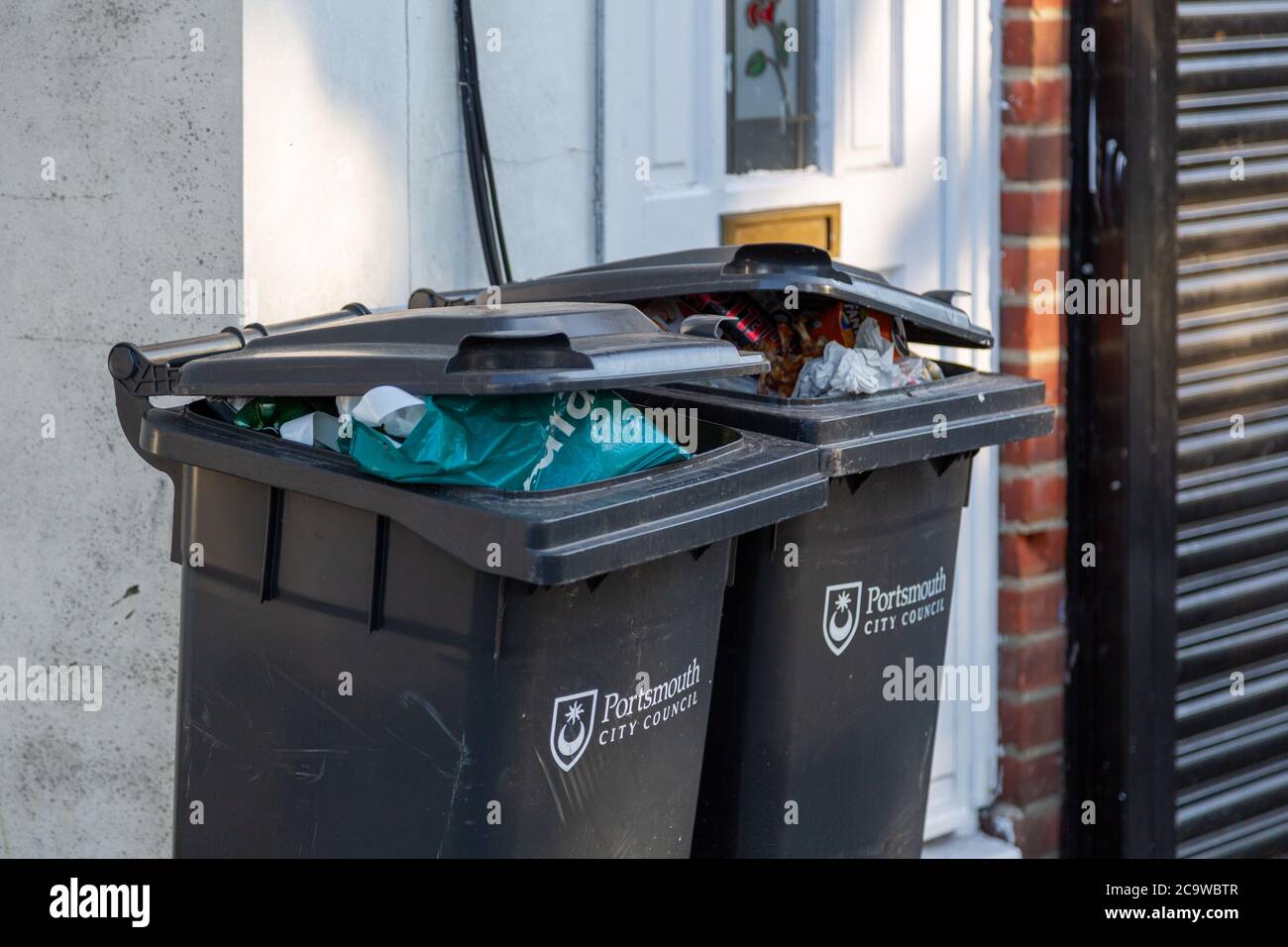 overflowing wheelie bins outside a house with Portsmouth city council on the front Stock Photo