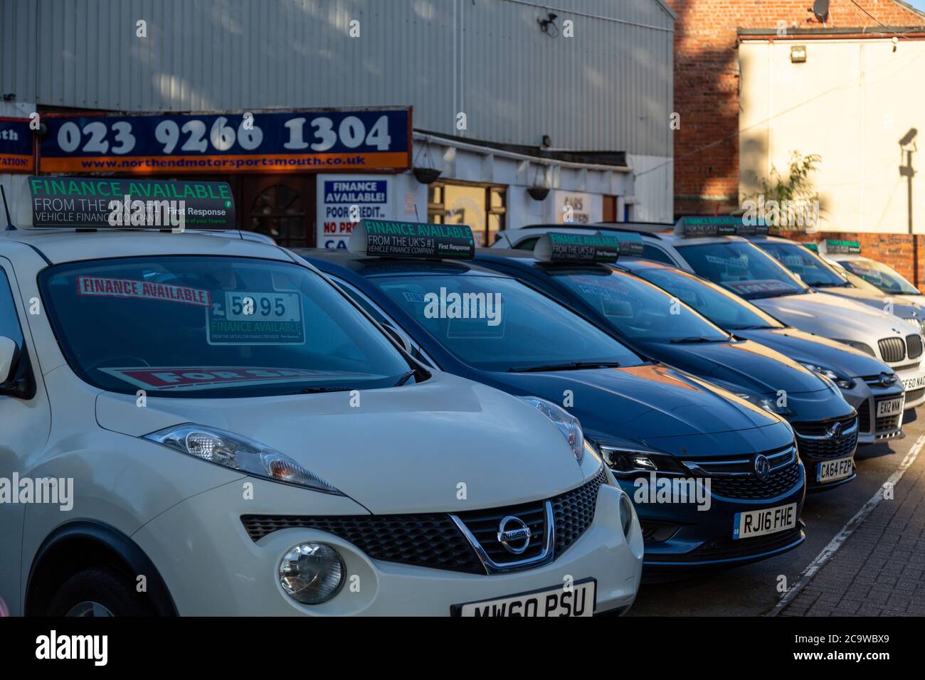 cars with prices in the windows on display outside a car showroom or car sales centre Stock