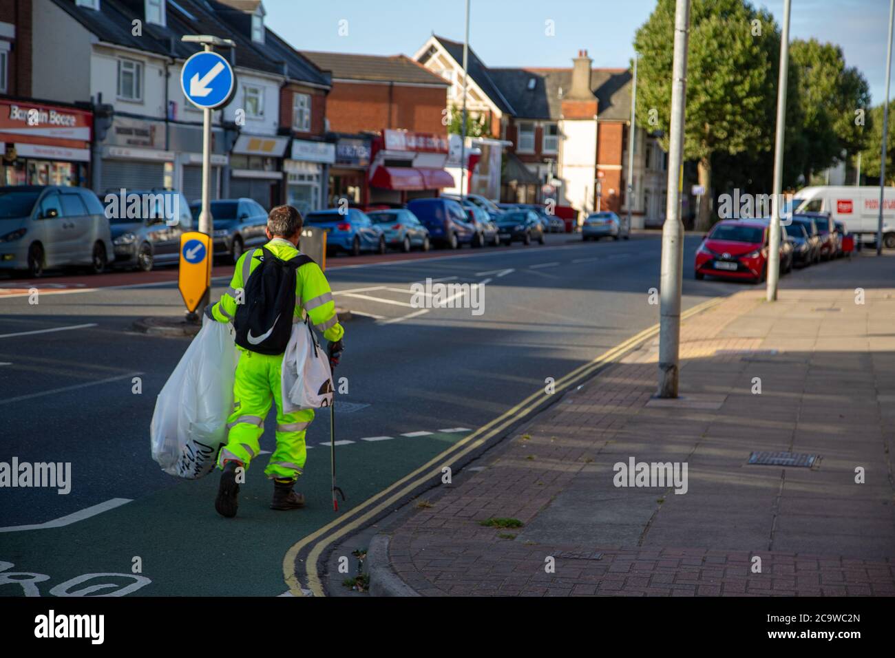 A council worker in high visibility clothing litter picking in the street Stock Photo
