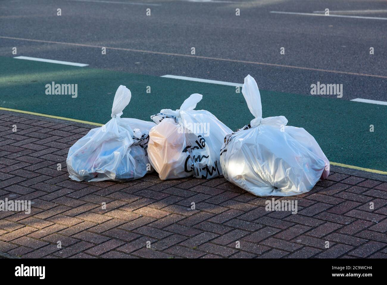 white rubbish bags or trash bags in the street ready for collection Stock Photo